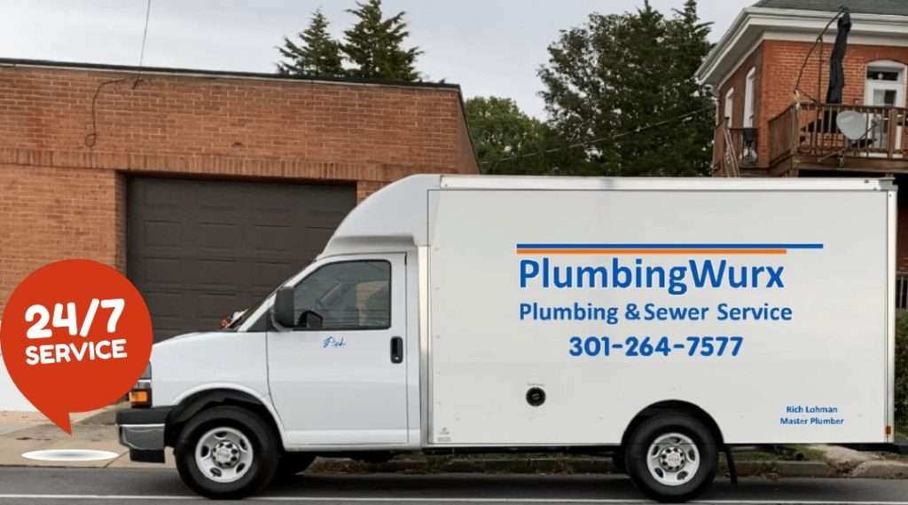 A white PlumbingWurx service van with contact information and a "24/7 Service" badge is parked in front of a brick building.