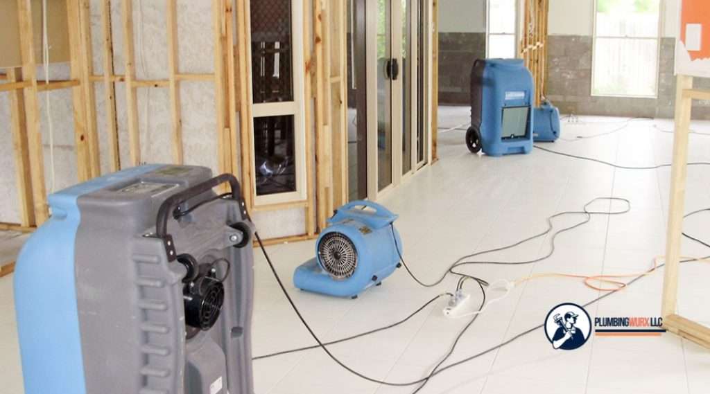 Blue dehumidifiers and air movers drying a construction site after water intrusion.